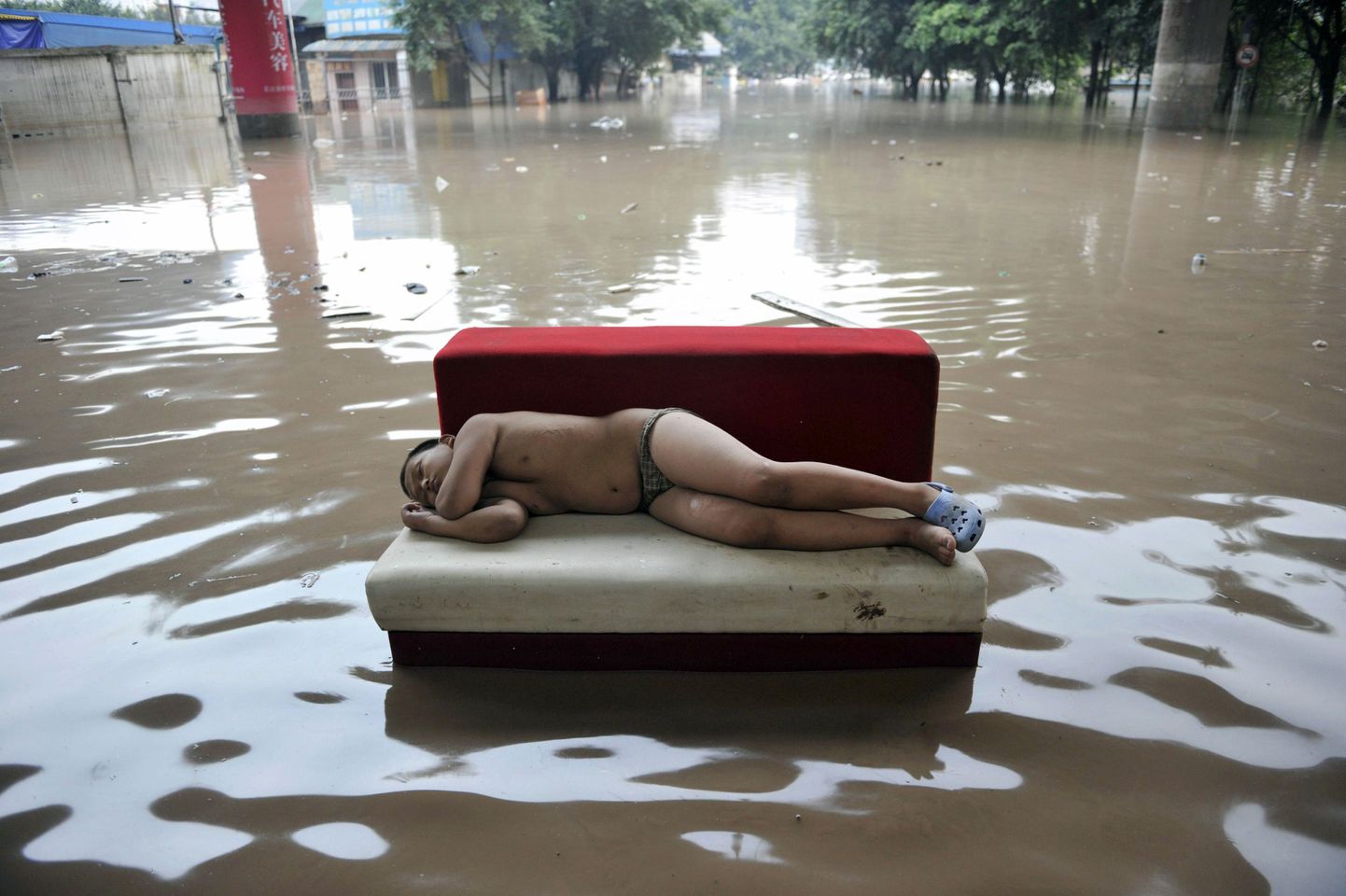 Laps magab sohval Chongqingis üleujutanud tänaval.