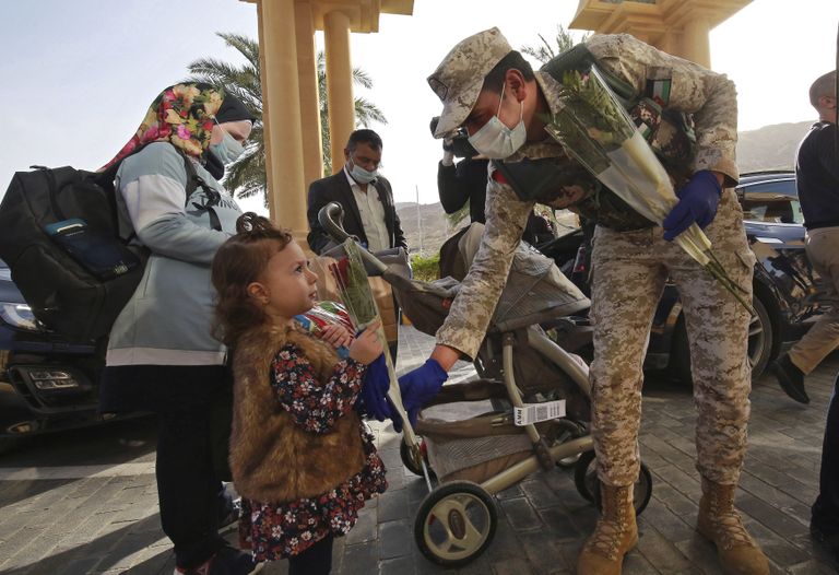 Jordaania sõdur karantiinist pääsenud lapsele lillekimpu ulatamas.