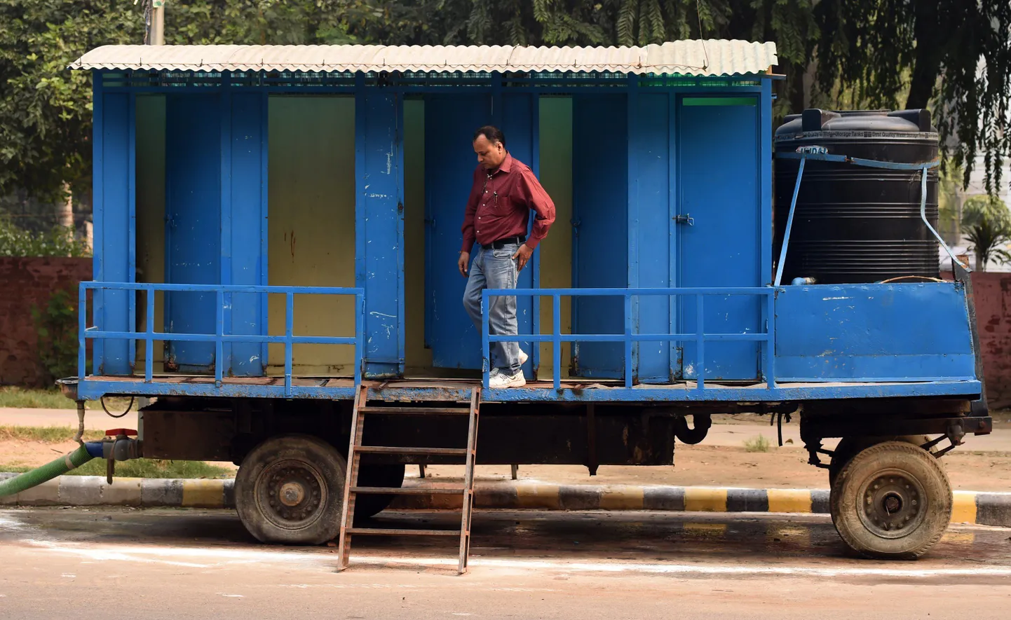 India mees liikuva tualeti ees. Mobiilseid tualette kasutatakse Indias lahendusena sanitaarprobleemidele.