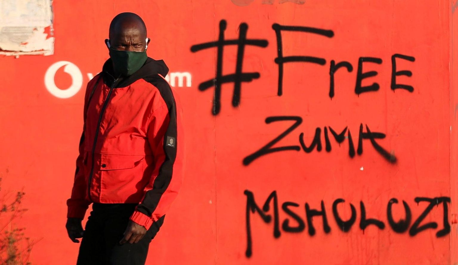 Mees kõnnib mööda seinast, millele on grafitiga kirjutatud «Vabastage Zuma».