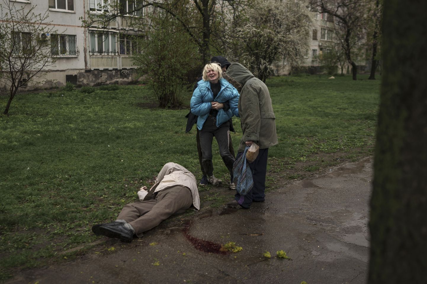 На фотографии женщина плачет над телом отца, убитого в ходе ракетной атаки российской армии в районе Харькова 18 апреля 2022.