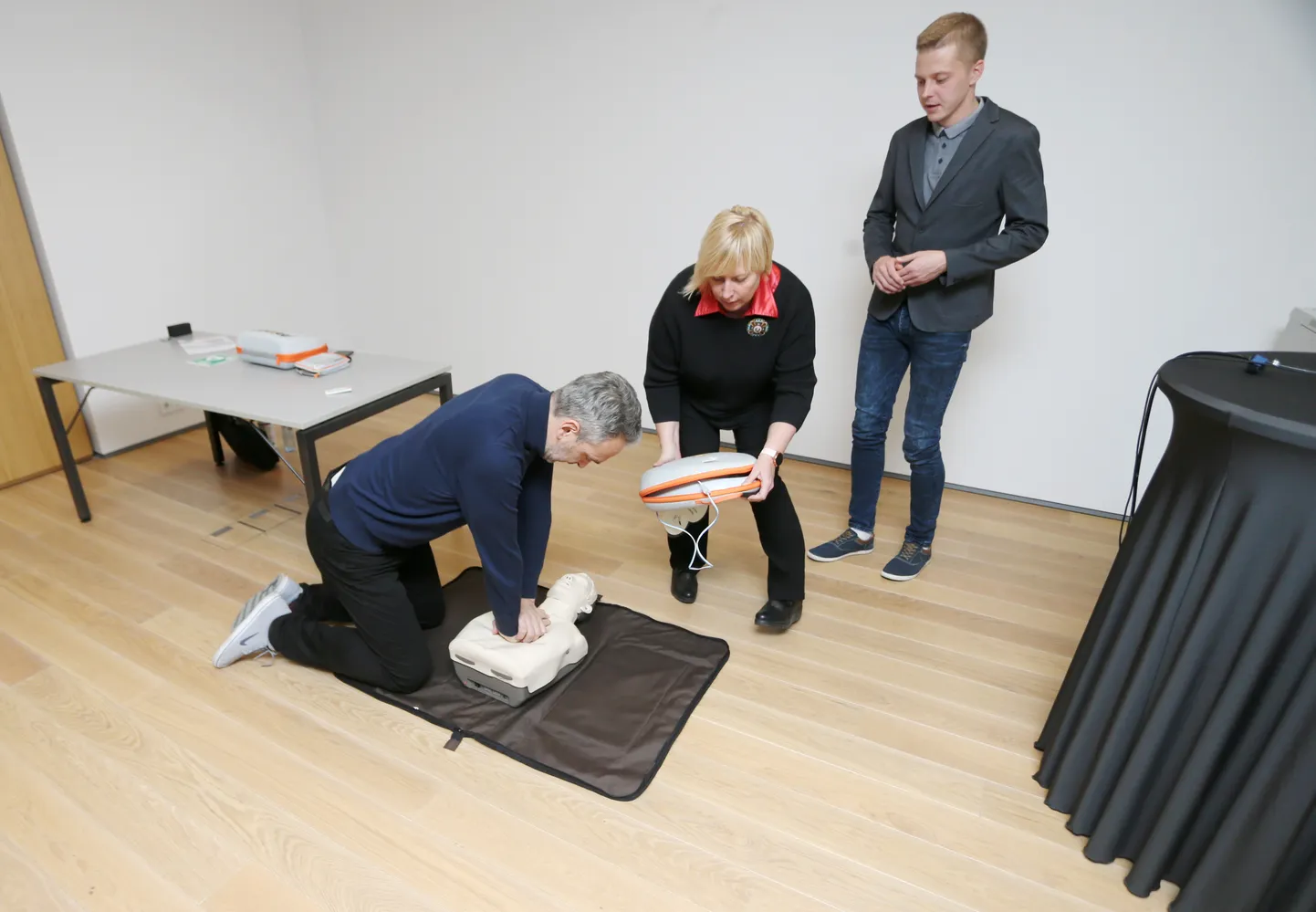 Elustamisaparaadi tutvustamine ERMis. Pildil ERMi avalike ja välissuhete juht Kalmar Kurs ja programmijuht Maarika Pokinen elustamist õppimas. Taga seismas Hansa Medicali müügiesindaja Tanel Tamm.