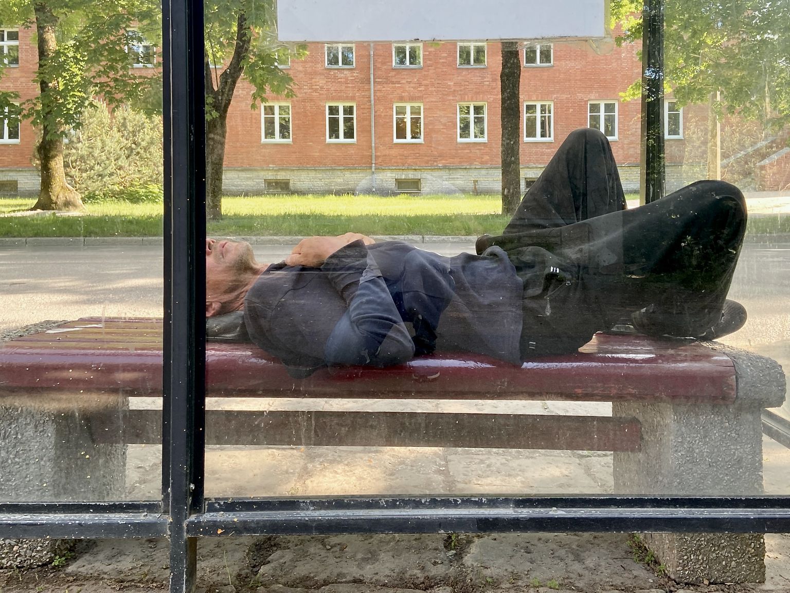 Выпивший человек спит на автобусной остановке в Нарве.