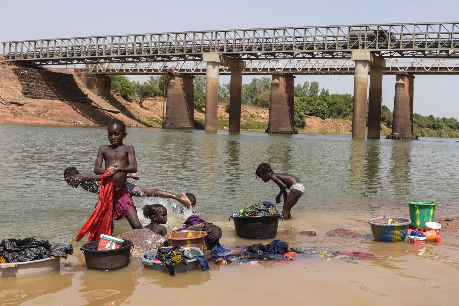 Senegali lapsed Gouloumbou jõe ääres ennast ja oma riideid loputamas. Nende vanemad peavad samal ajal jõehobuvalvet.