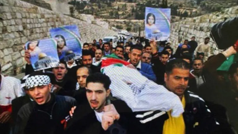 Скорбящие на похоронах дочери Басама держат ее фотографии