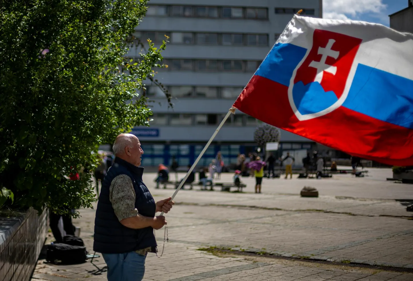 Slovakkia lippu ja palvehelmeid hoidev mees toetamas Banská Bystrica haigla ees seal intensiivravi osakonnas viibivat peaministrit Robert Ficot.