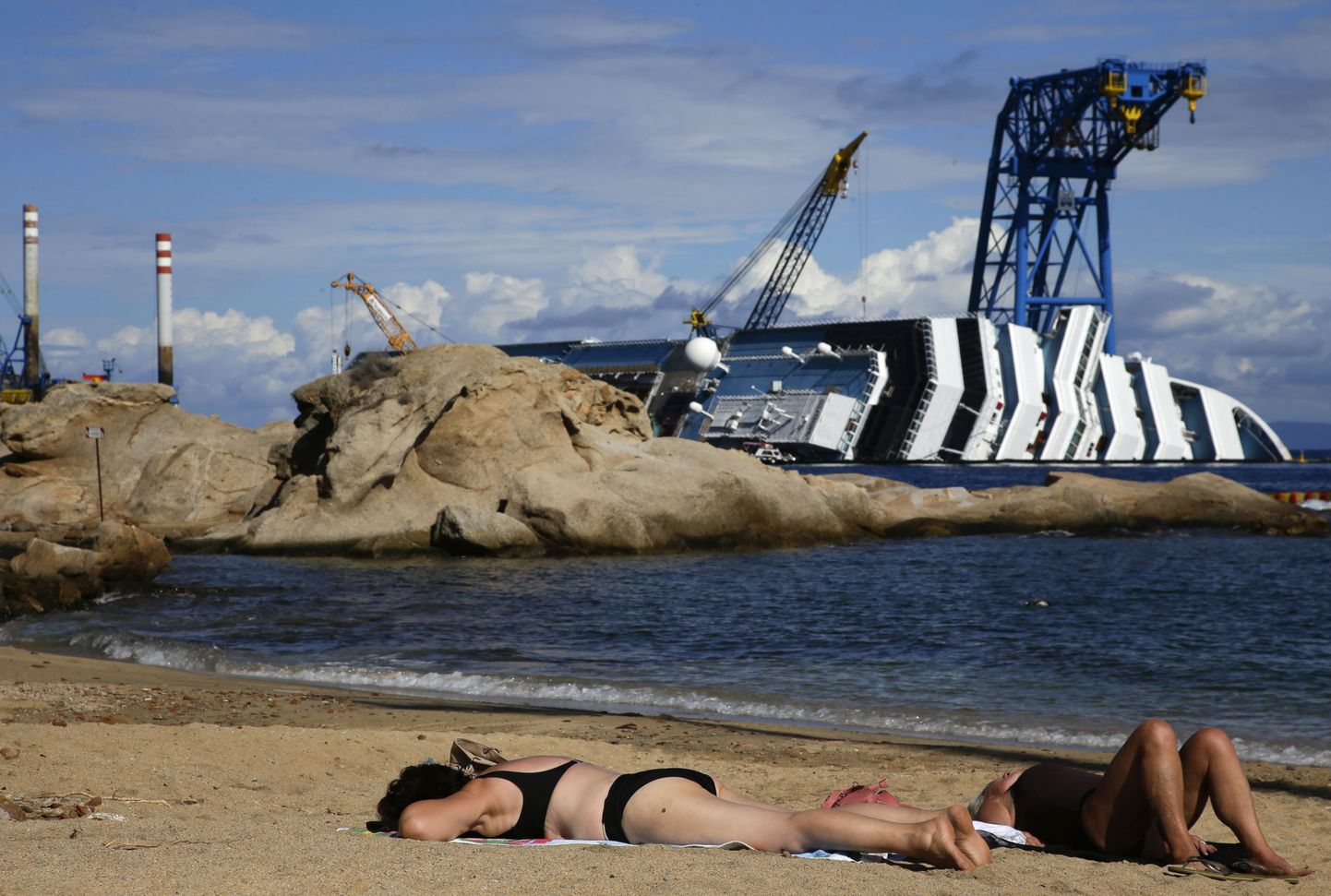 Päevitajad rannas kruiisilaeva Costa Concordia vraki lähedal.