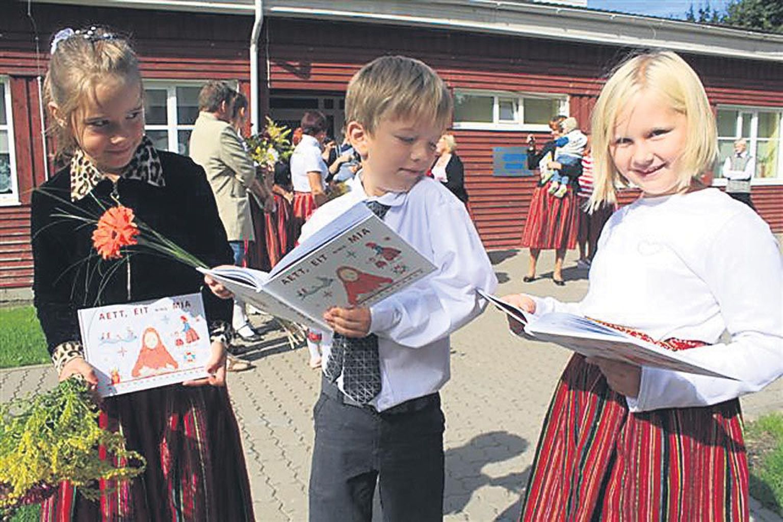 Kihnu kooli esimese klassi õpilased Kärolin Lamend, Rasmus Lilles ja Pilleriin Köster uurisid eile koolimaja ees kihnukeelset raamatut “Aett, eit ning mia”, mis ongi nende esimene õpik.