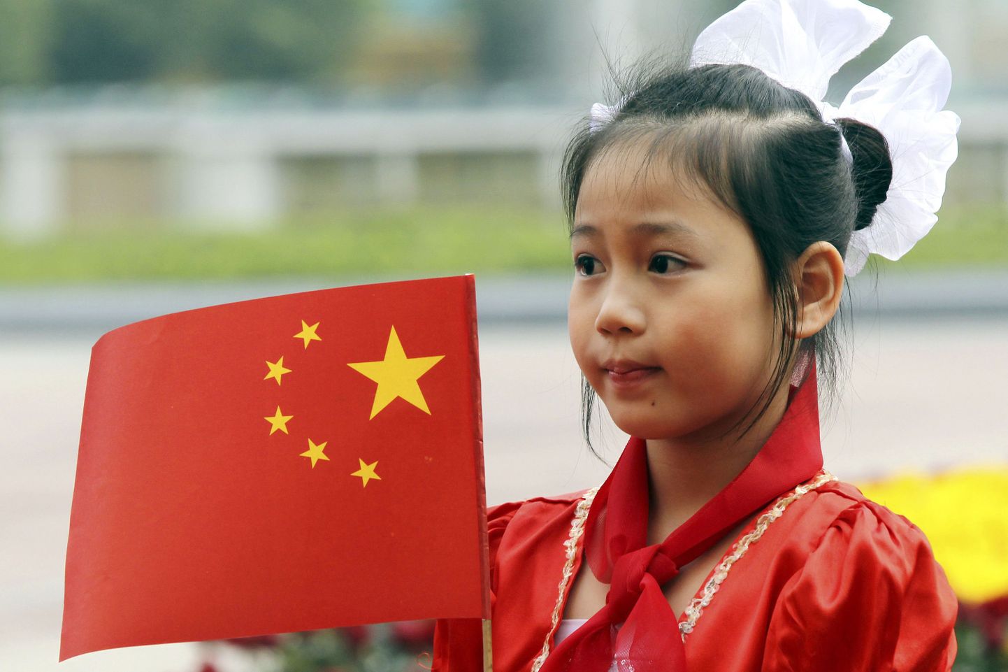 Üleeilne foto Vietnami tüdrukust, kel käes liiga palju tähti sisaldav Hiina lipp.