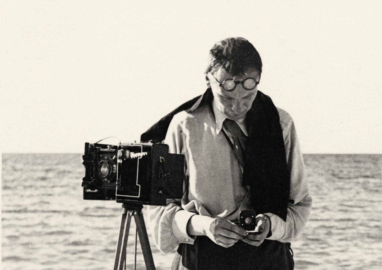 Carl Sarap mõõdab rannal eksponomeetriga säriaega, et siis pildistada kaameraga Welta Dupla.