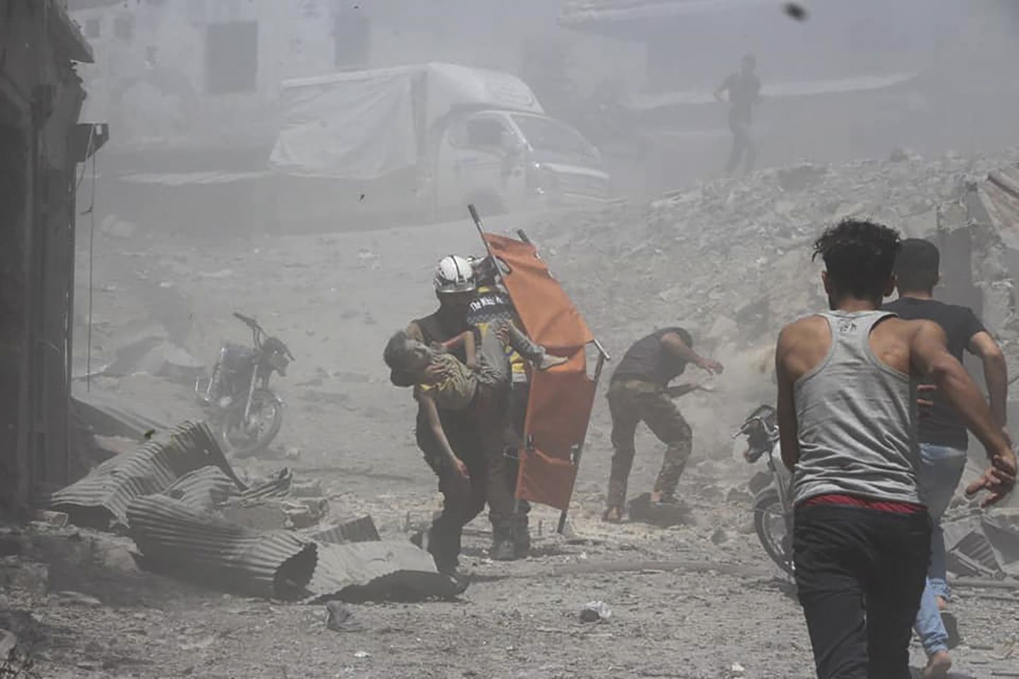 Süüria tsiviilkaitse foto näitab rühmituse töötajat kandmas Süüria valitsuse õhurünnakus Jisr al-Shughuri linnas vigastada saanud poissi.