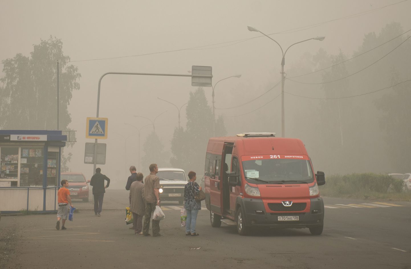Ust-Ilimski bussipeatuse ja seal seisvate inimeste taustal on näha metsapõlengute suitsu, mis on enda alla matnud üle 80 000 elanikuga linna.