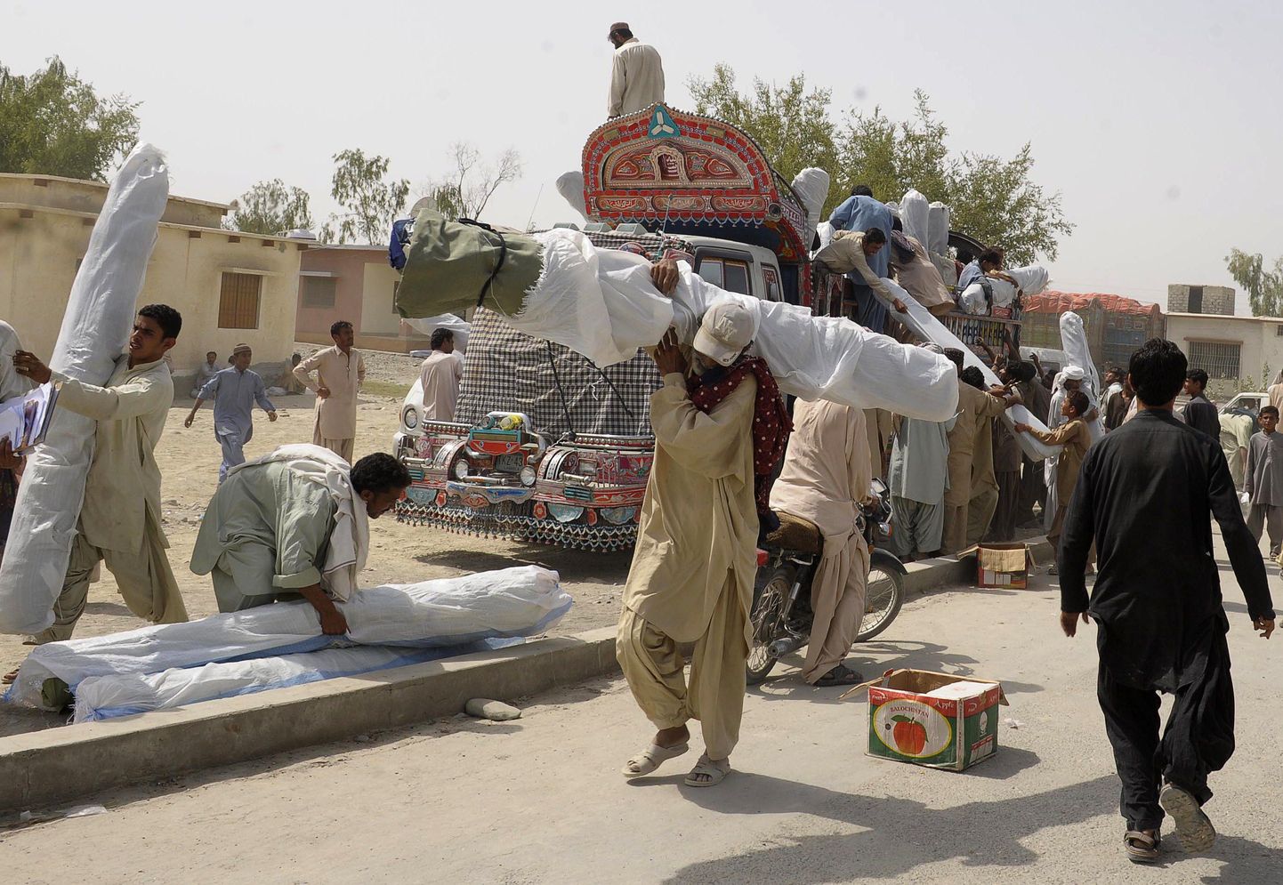 Pakistani teisipäevasest maavärinast eluga pääsenud inimesed kannavad jaotuspunktist saadud telke.