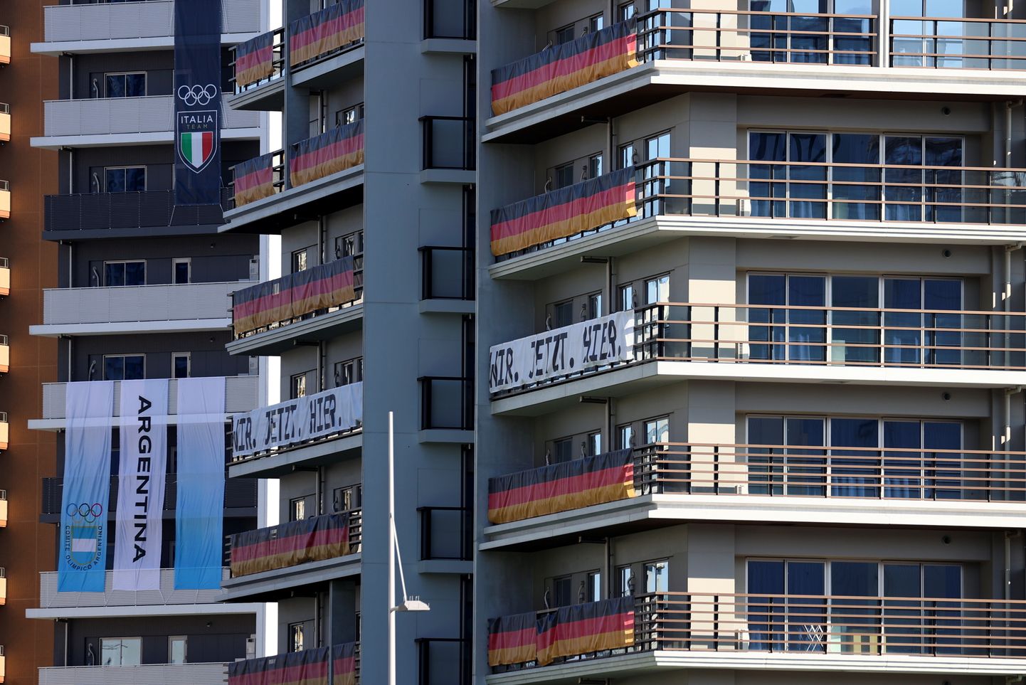 Олимпийская деревня отмечает расположение участников на балконах национальными флагами.