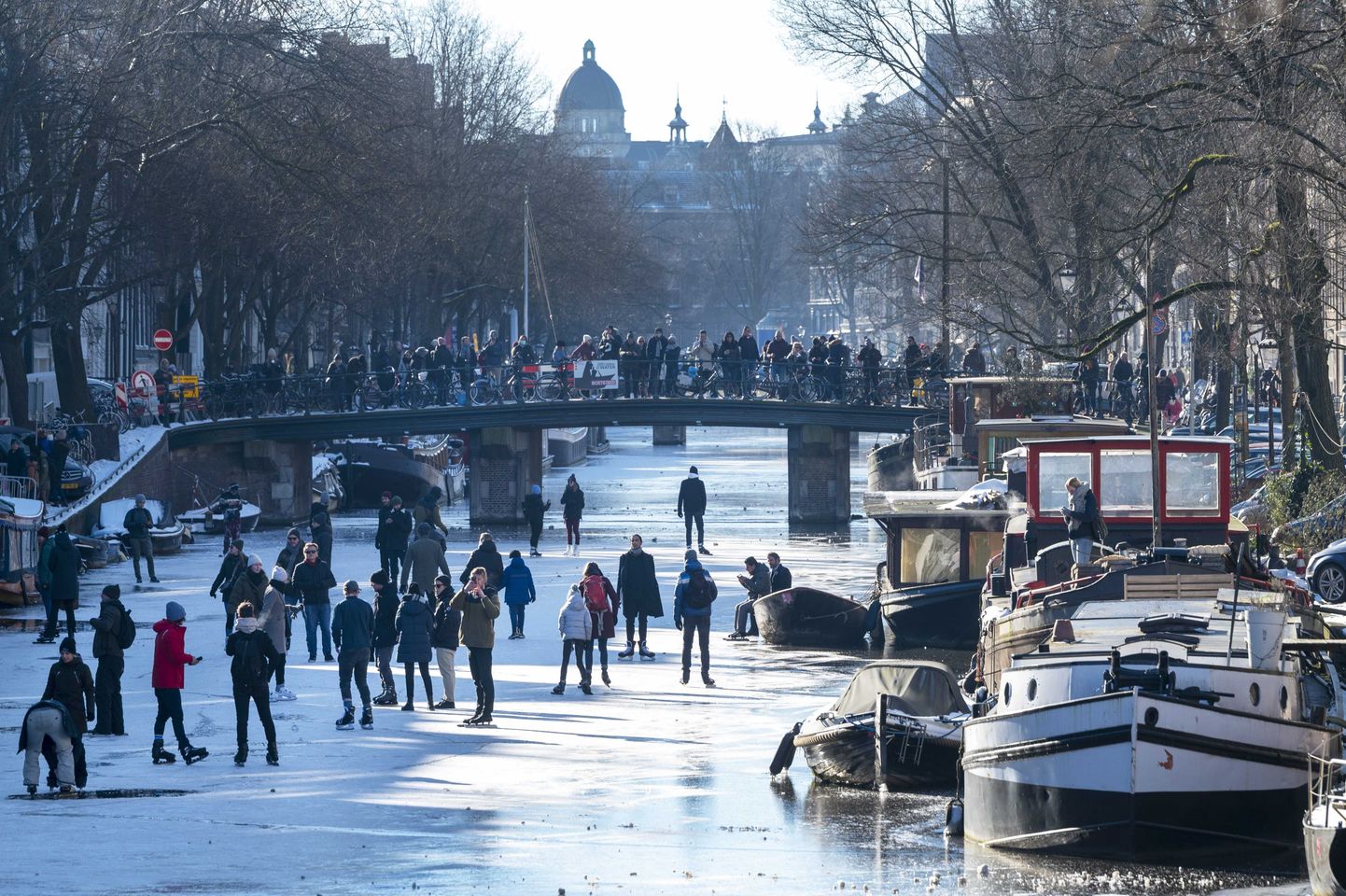 Inimesed jalutamas ja uisutamas Amsterdami kanalil.