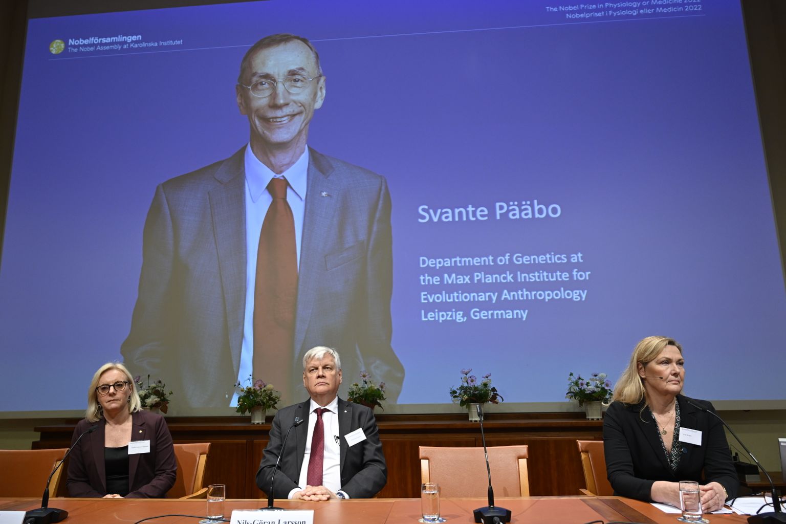 (L-R) Member of the Nobel Committee for Physiology or Medicine (L-R) Gunilla Karlsson-Hedestam, Chair of the Nobel Committee for Physiology or Medicine Nils-Goran Larsson and member of the Nobel Assembly at Karolinska Institutet Anna Wedell listen to the announcement of the 2022 Nobel laureate in physiology and medicine Svante Pääbo of Sweden (seen on the screen) during a press conference at the Karolinska Institute in Stockholm,