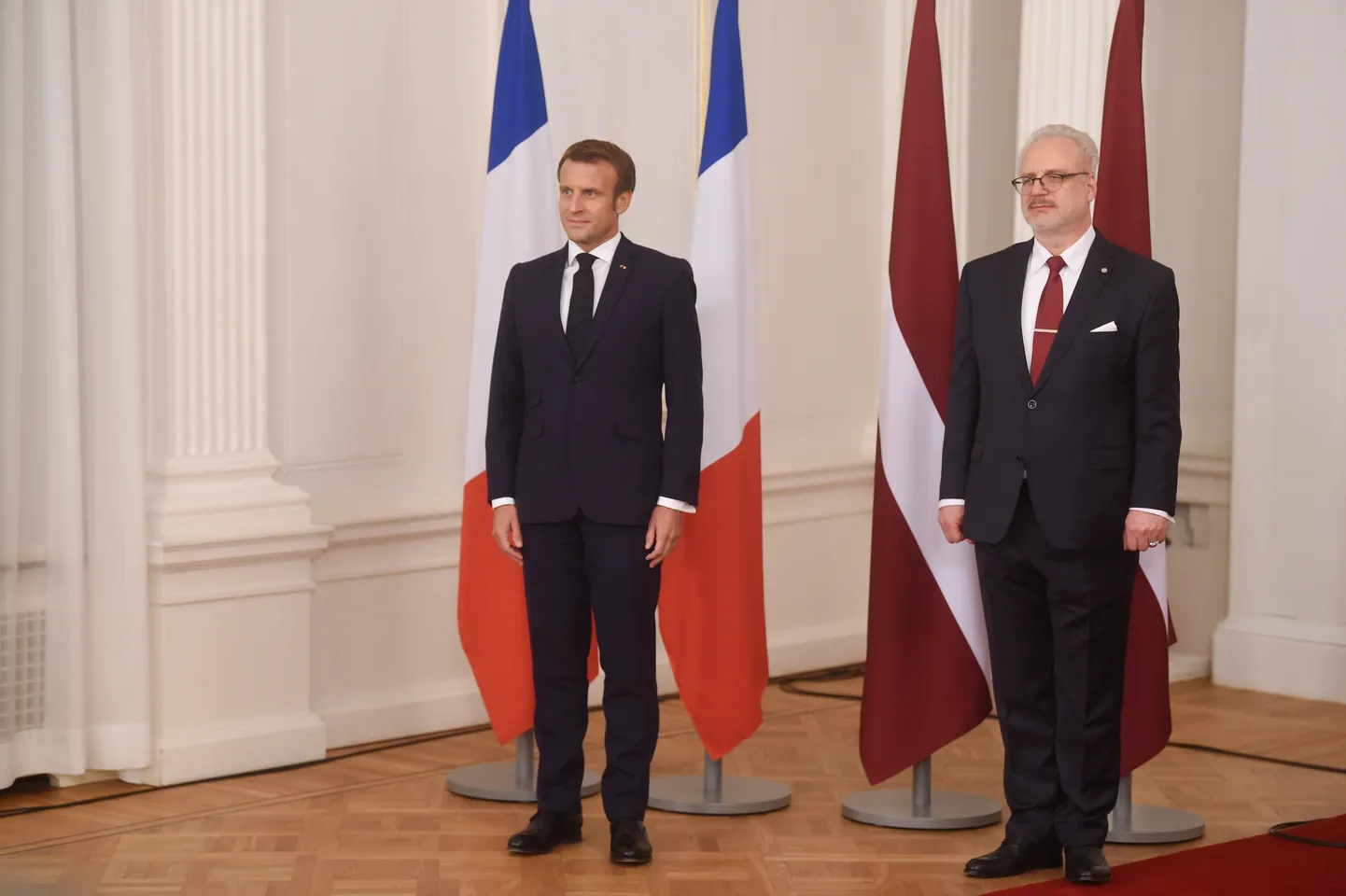 Latvijas prezidents Egils Levits (no labās) un Francijas prezidents Emanuels Makrons fotografējas pie abu valstu karogiem pirms paziņojuma presei Rīgas pilī.