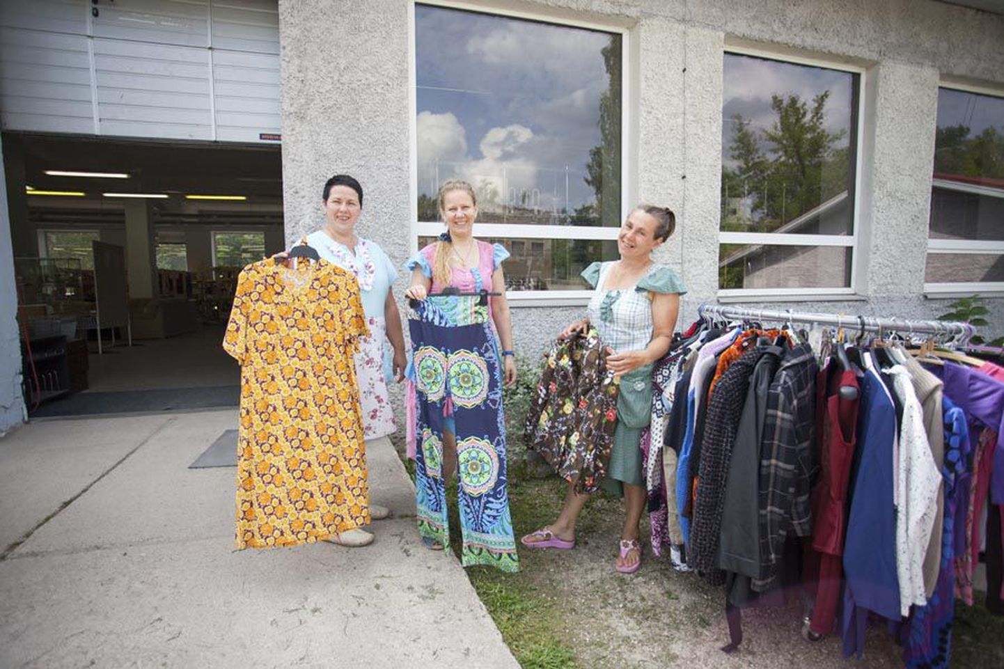 Taaskasutuskeskuses Sahtel töötavad (vasakult) Eve Kavak, vabatahtlik Marge Rell ja klienditeenindaja Mall Kongo. Naised kannavad taaskasutatud kangast kleite ja näitavad menukaupa retrorõivaid.