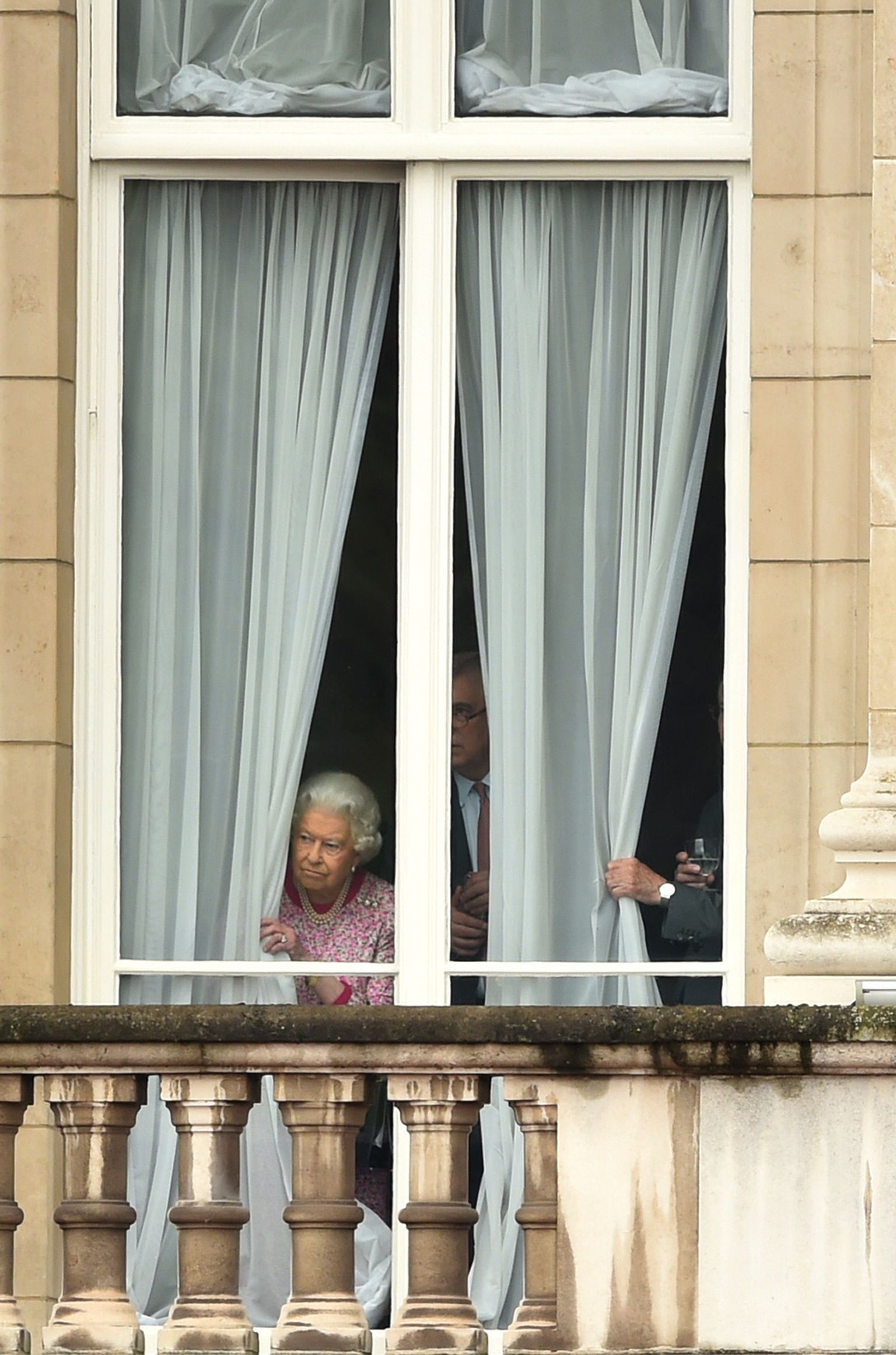 Kuninganna Elizabeth II vaatab Buckinghami palee aknast välja.
