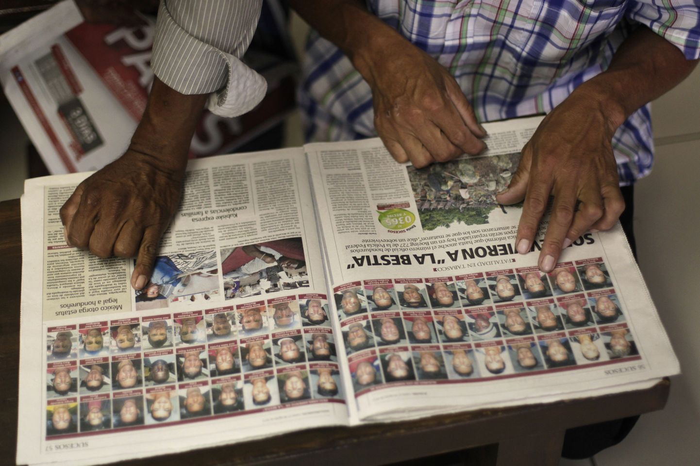 Rööbastelt välja sõitnud kaubarongil sõitnud immigrantide sugulased vaatavad Hondurase välisministeeriumis ellujäänute fotosid.
