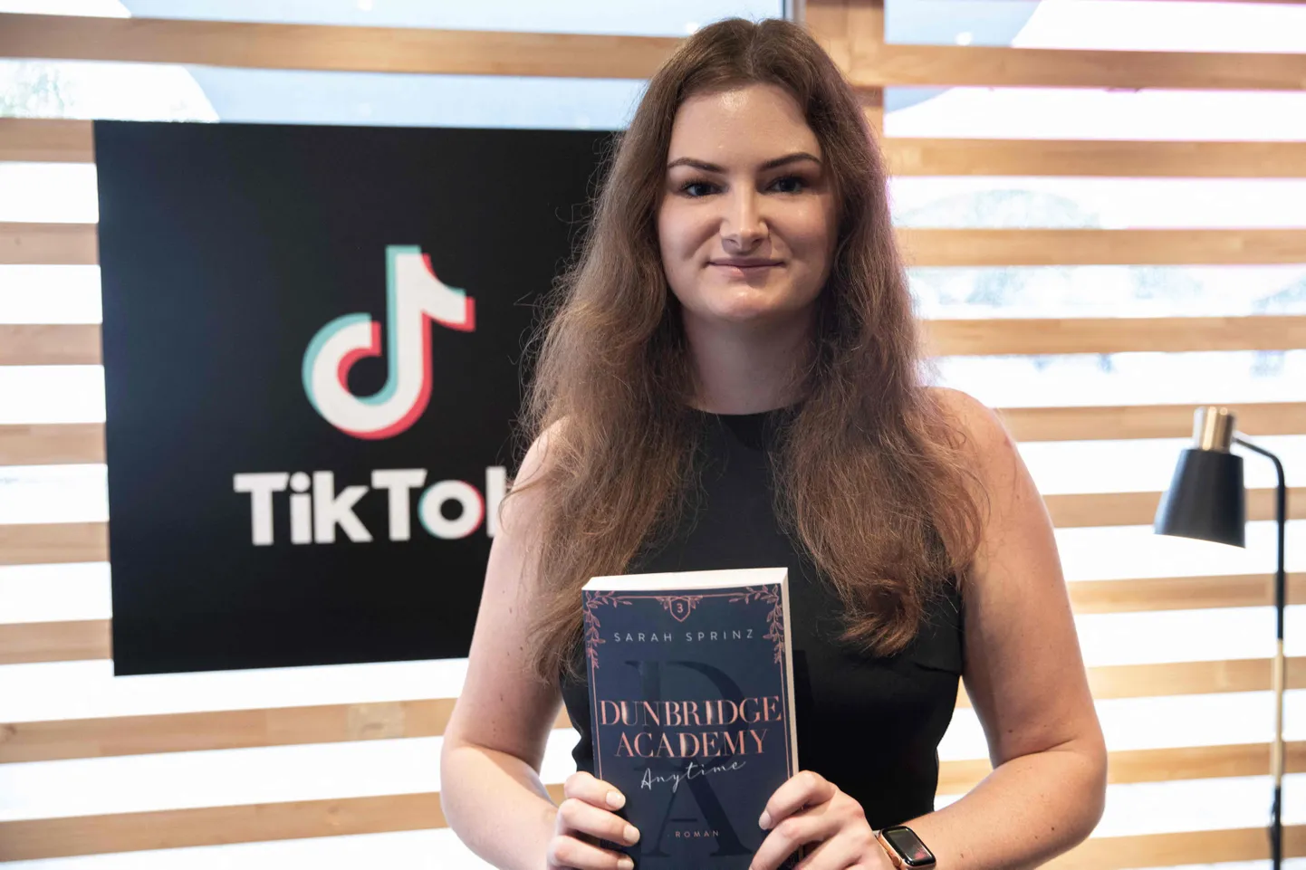 Naine TikTik logo ees. Pilt on illustratiivne
