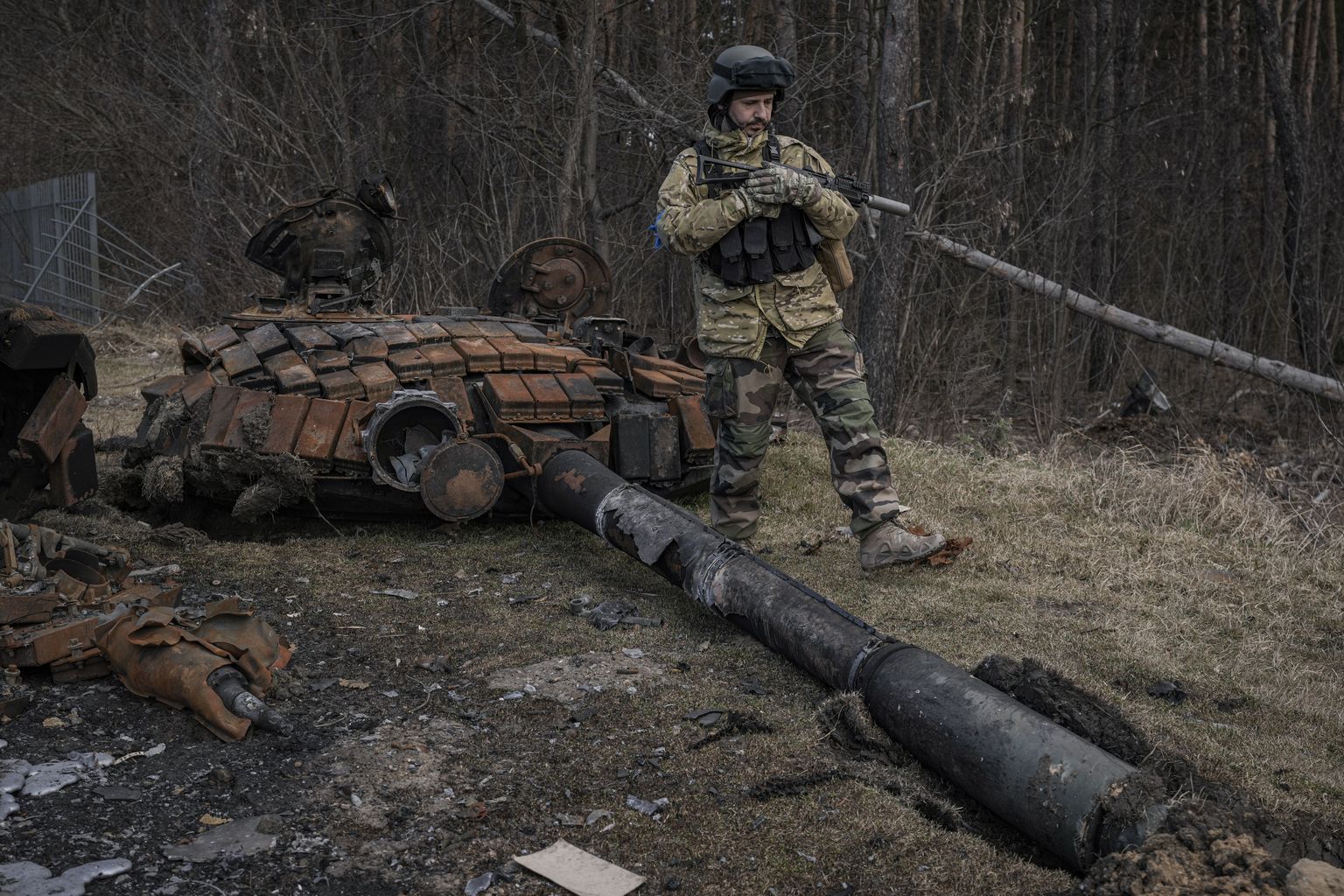 A Ukrainian serviceman walks next to the wreck of a Russian tank in Stoyanka, Ukraine, Sunday, March 27, 2022.