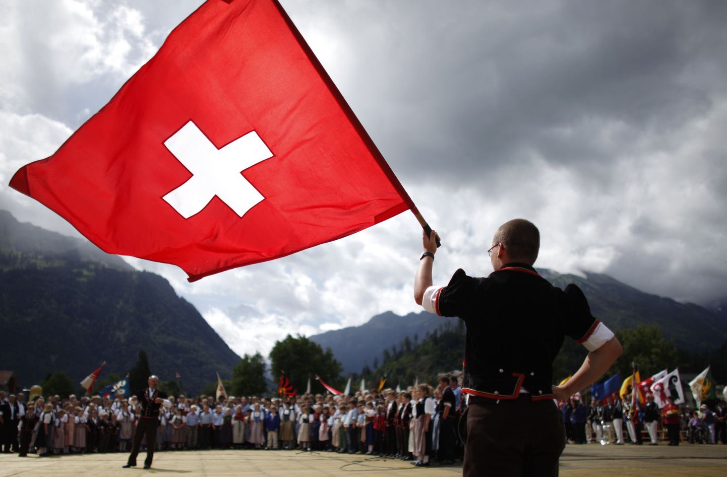 Rahvarõivais šveitslane riigilippu lehvitamas.