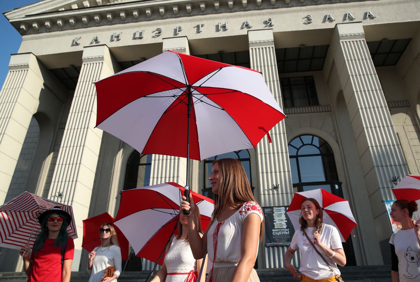 Naised kandmas Minskis puna-valgeid vihmavarje. Kogu riigis peavad kommunaalteenistused puna-valge sümboolikaga visa võitlust.