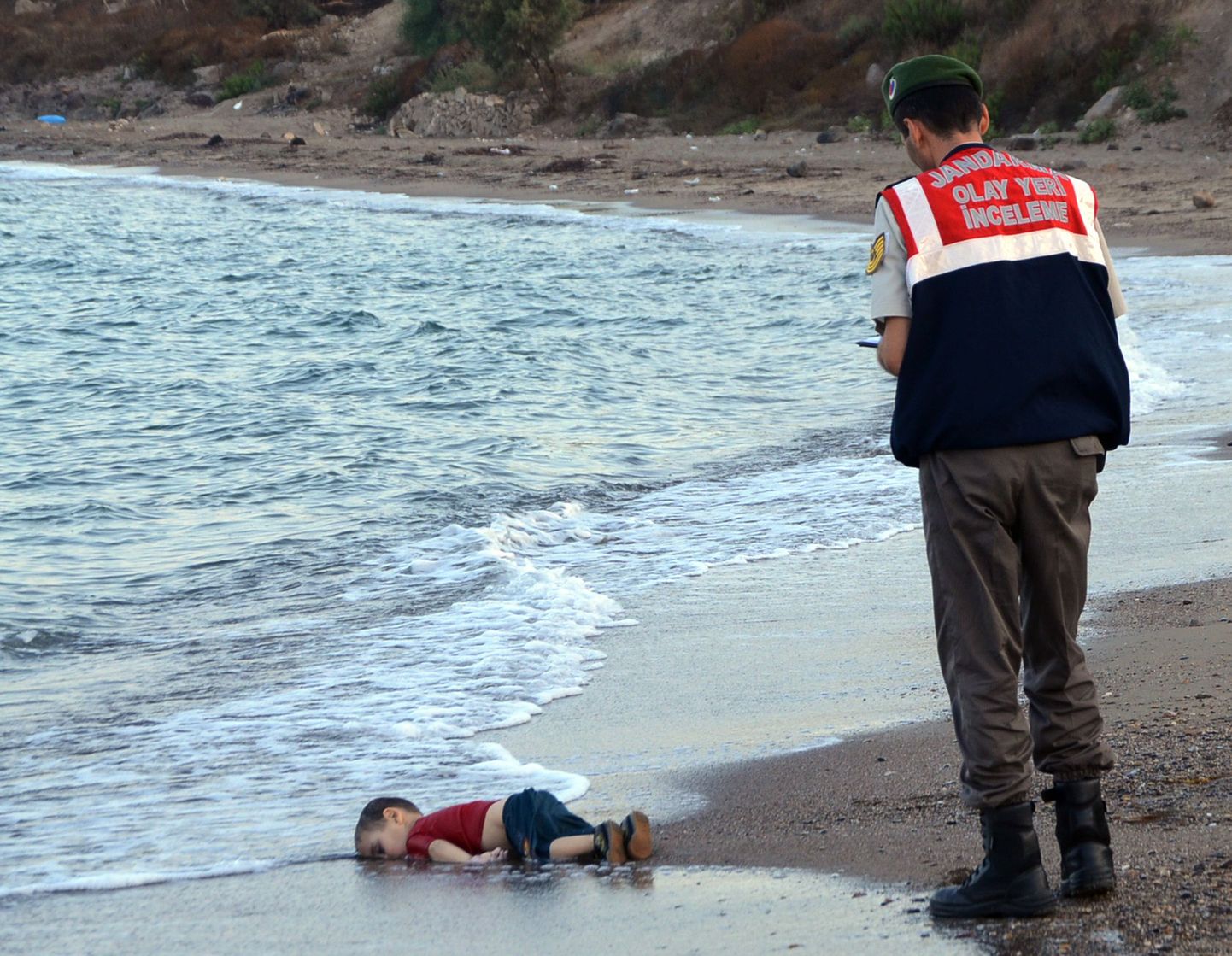 Elutu Aylan ja Türgi sandarm, kes lapse laiba rannast üles korjas.