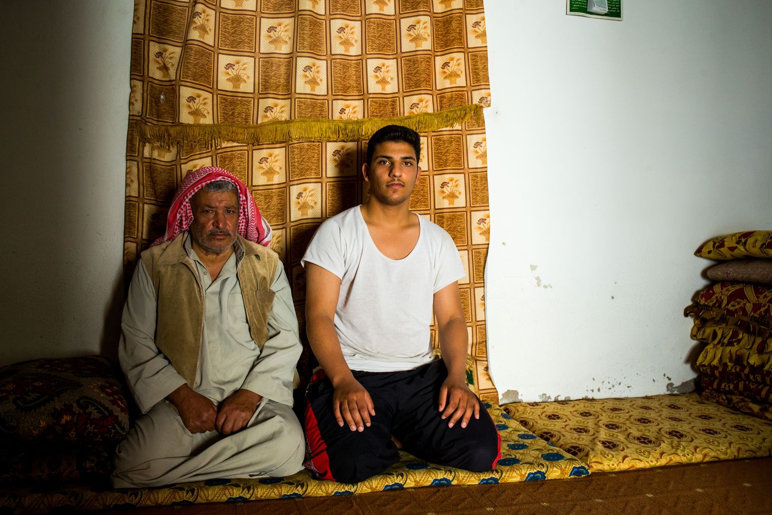 Süürlane Moused Ahmed Fandi koos poja Waji Mousaga oma ajutises kodus. Põrandale istumiseks pandud madratsid ja padjad on saadud kingituseks kohalikelt jordaanlastelt.