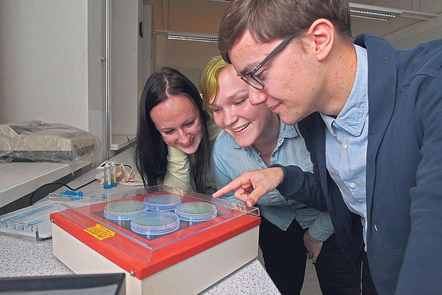 Need bakterid, kes võtsid võõra DNA vastu, hakkasid helendama. Tulemusi vaatavad Tamme gümnaasiumi loodusklassi abituriendid Sigrid Soosaar (vasakult), Triin Hunt ja Karl Pütsepp.