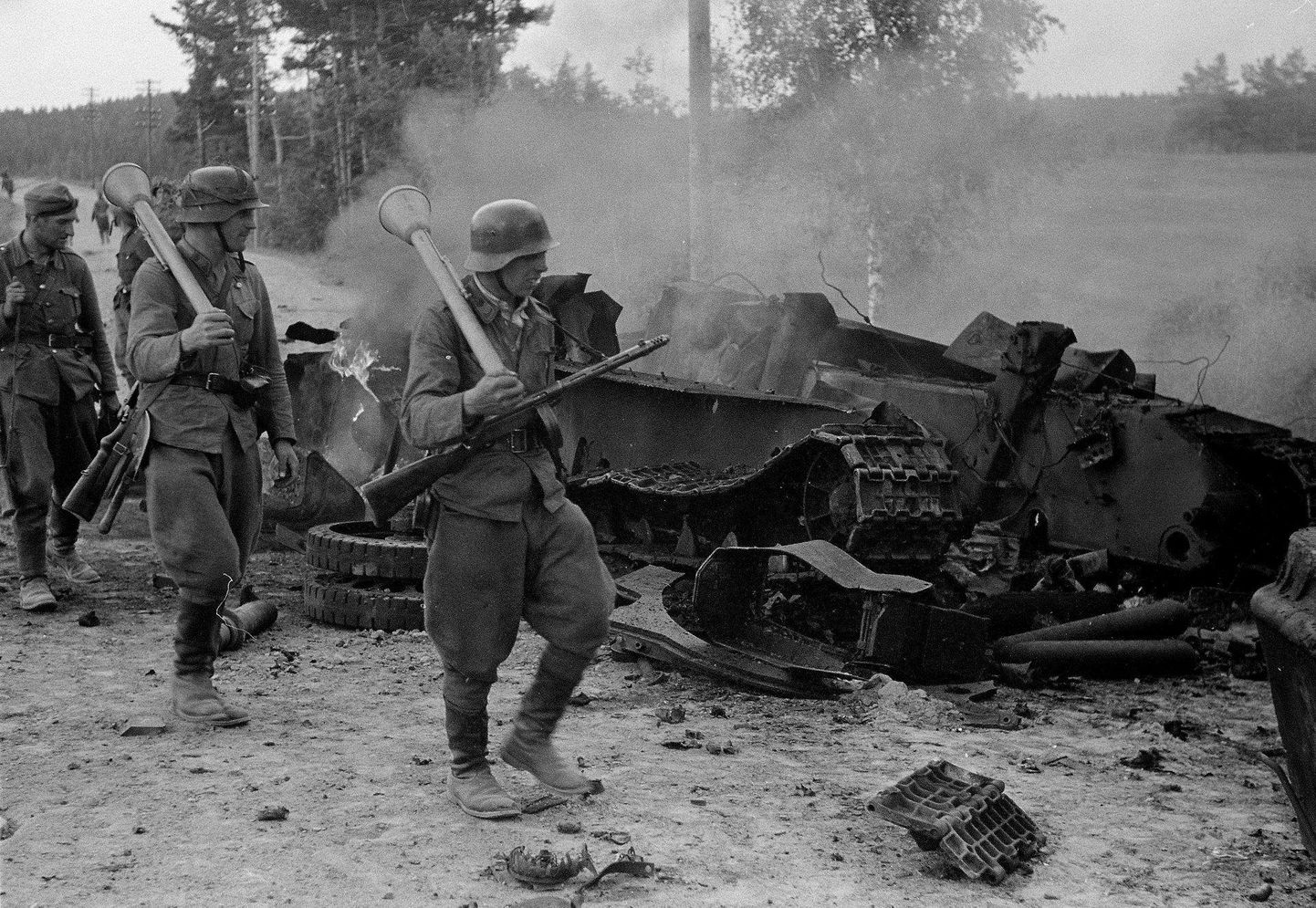 Soome sõdurid, kandes tankitõrjegranaadiheitjat oma õlgadel, mööduvad hävitatud Nõukogude tanki T-34 riismetest Tali-Ihantala lahingus.