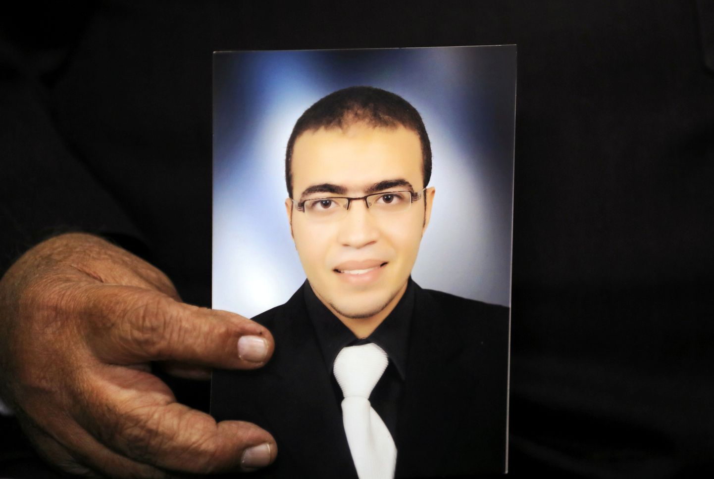 Реда Хамами, отец Абдуллы, показывает фотографию сына журналистам