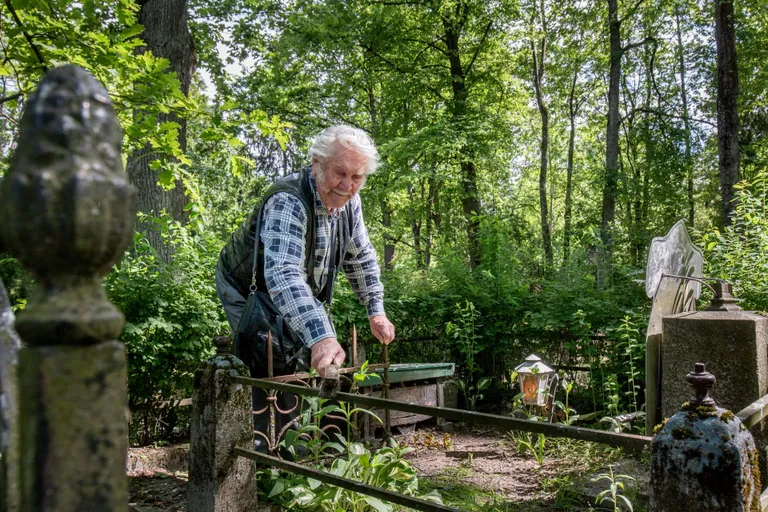 Aleksander Neigaus nühib traat- ja terasharja ning noaga hauaplatsi ümbritsevat metallist piiret. Mingid plekid kuigivõrd isegi kaovad, aga mitte täielikult.