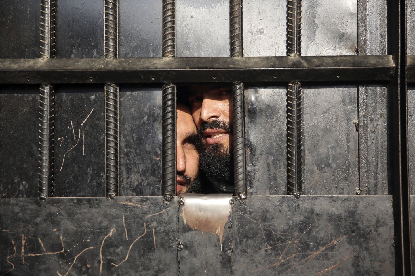 Vangistatud talibid piilumas läbi vangla ukseluugi.