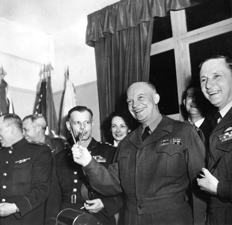 7. mai 1945 Prantsusmaa Reims. Pildil keskel liitlasvägede ülemjuhataja Euroopas, USA kindral Dwight Eisenhower, kes hoiab sulepäid, millega Saksamaa relvajõudude ülemjuhatuse esimehe asetäitja Alfred Jodl kirjutas alla Saksamaa tungimusteta kapituleerumise dokumendile