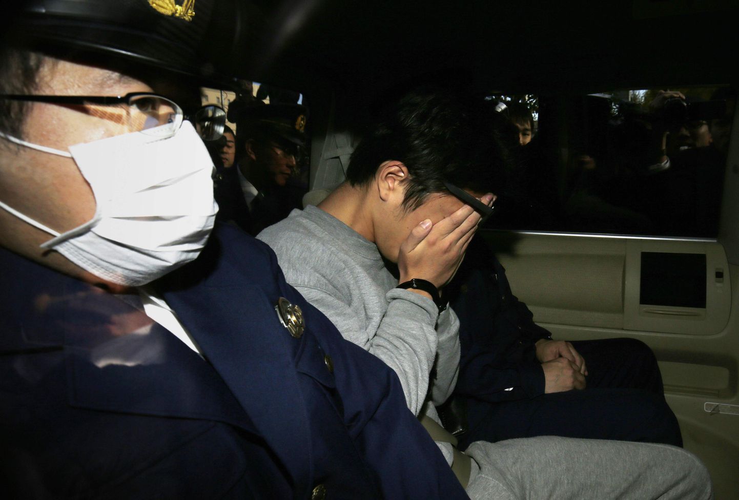 Takahiro Shiraishi varjamas oma nägu fotograafide eest, kui teda viidi prokuratuurist politseijaoskonda 1. novembril 2017. aastal.