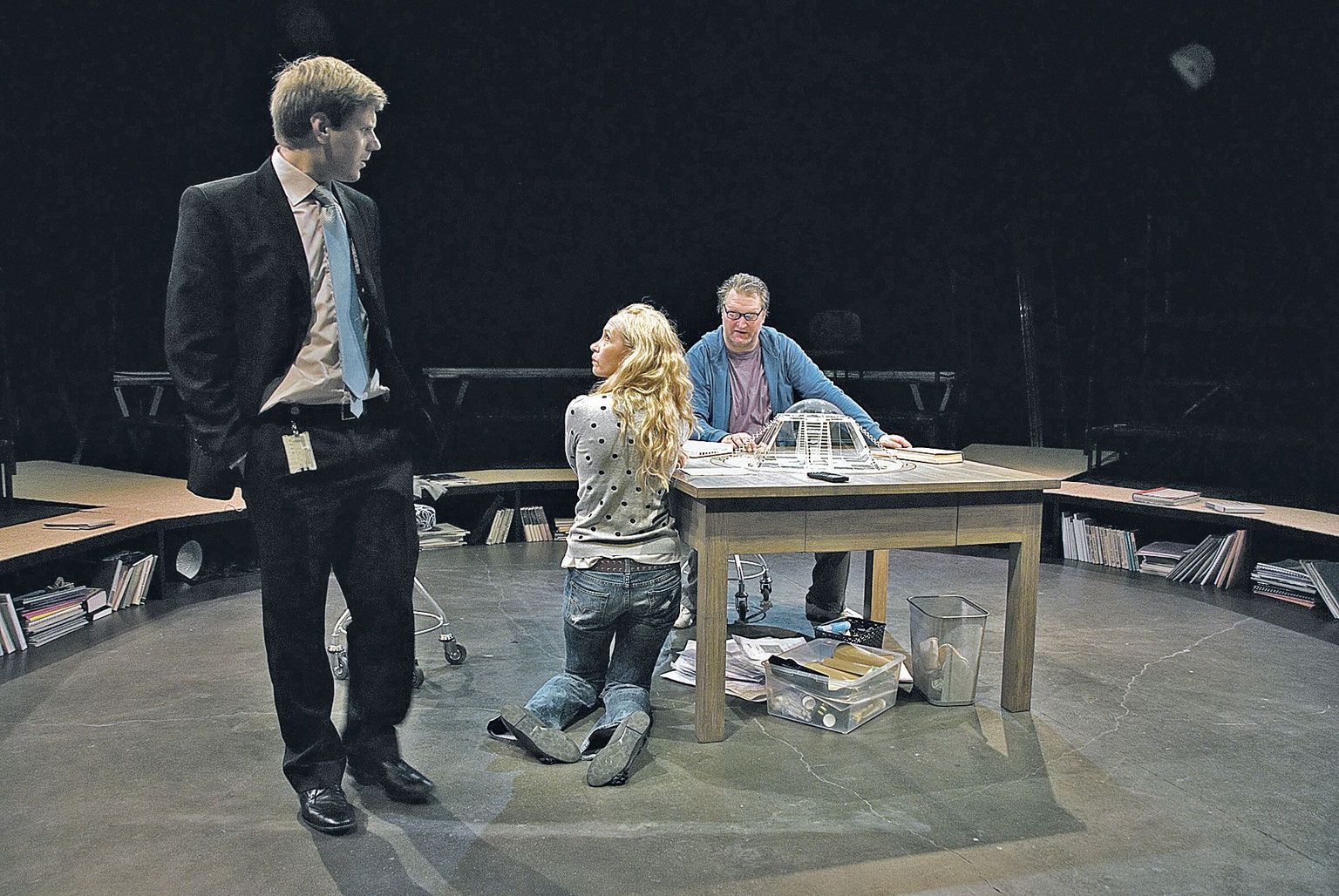 Laual on klaasist maja makett. Selle juures on lavastaja Olavi (paremalt, Indrek Taalmaa) ja tema naine, teatrikunstnik Saara (Marika Barabanštšikova). Nende vestlust jälgib lavastuste produtsent Aleks (Karol Kuntsel).