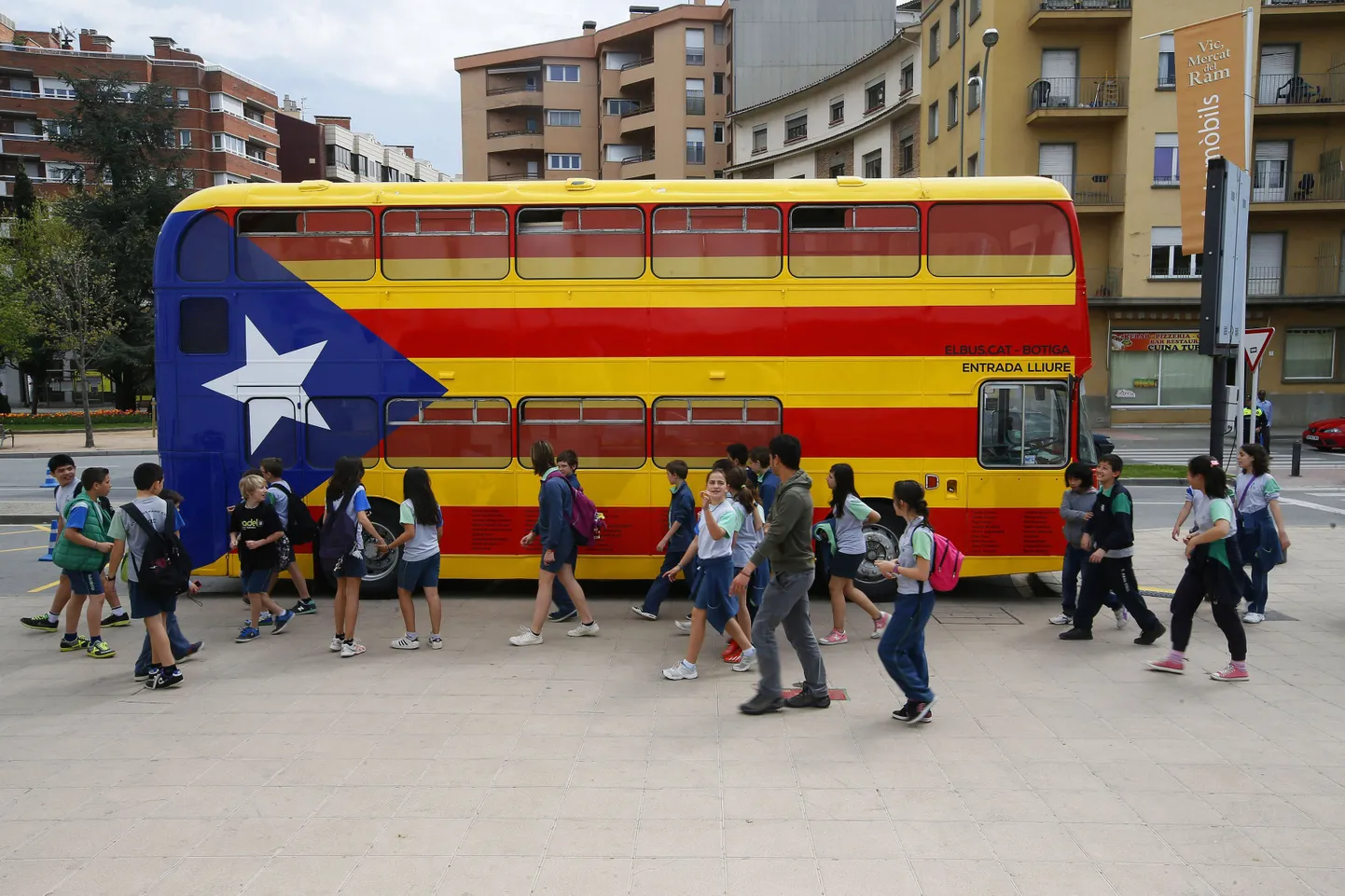 Koolilapsed Vicis katalaani iseseisvuse pooldajate lipu värvides bussi ees.