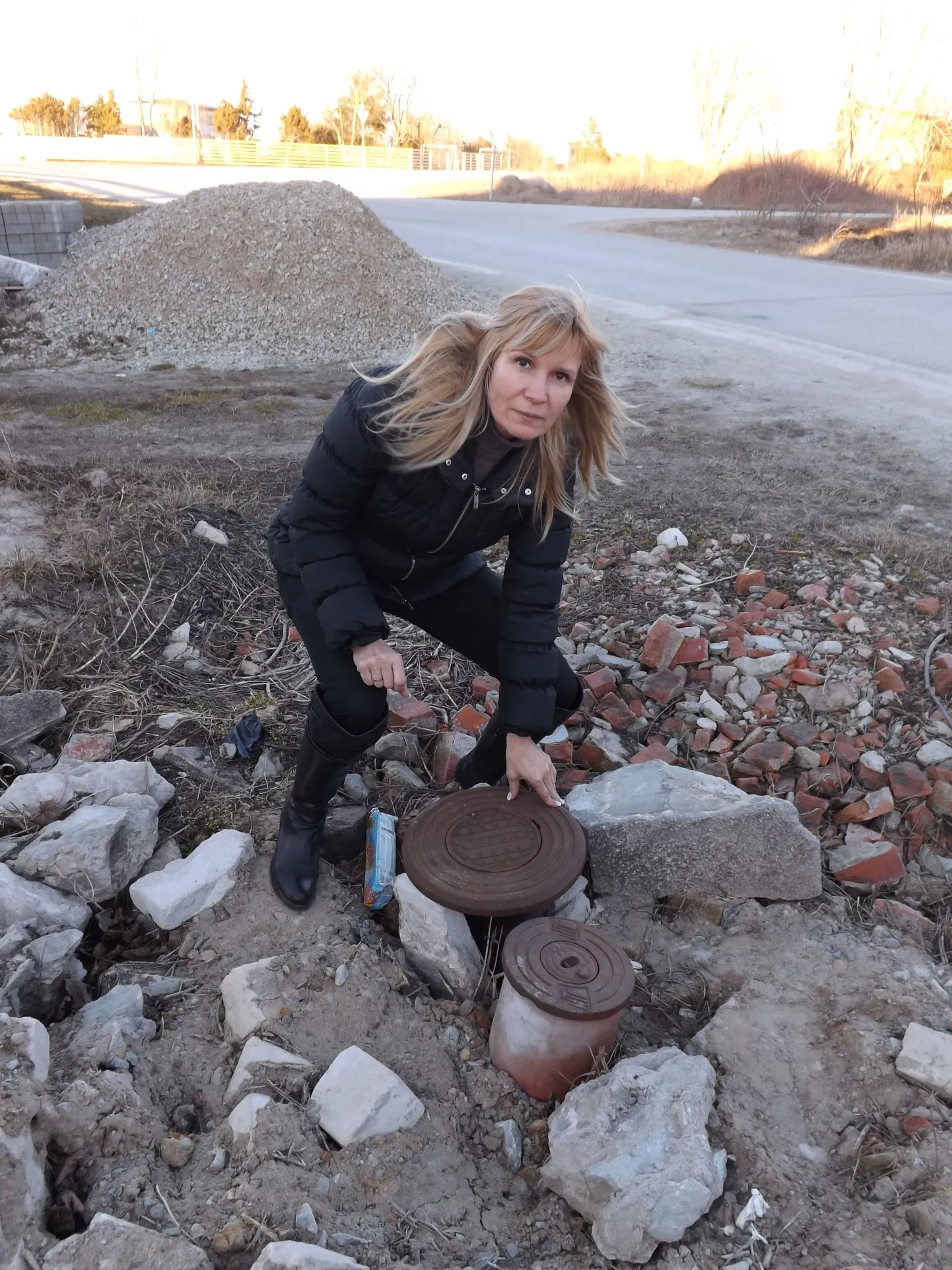 Хозяйка половины парного дома в деревне Мурасте Лариса Крюченко показывает канализационный люк, в глубь которого уходят корни их с соседом конфликта, который вот-вот перейдет в судебную стадию.