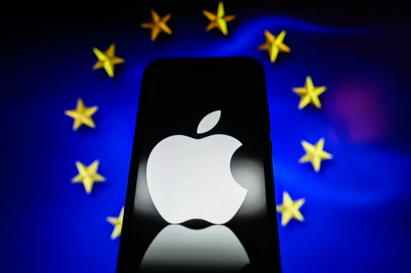 Смартфон с логотипом Apple на фоне флага ЕС.