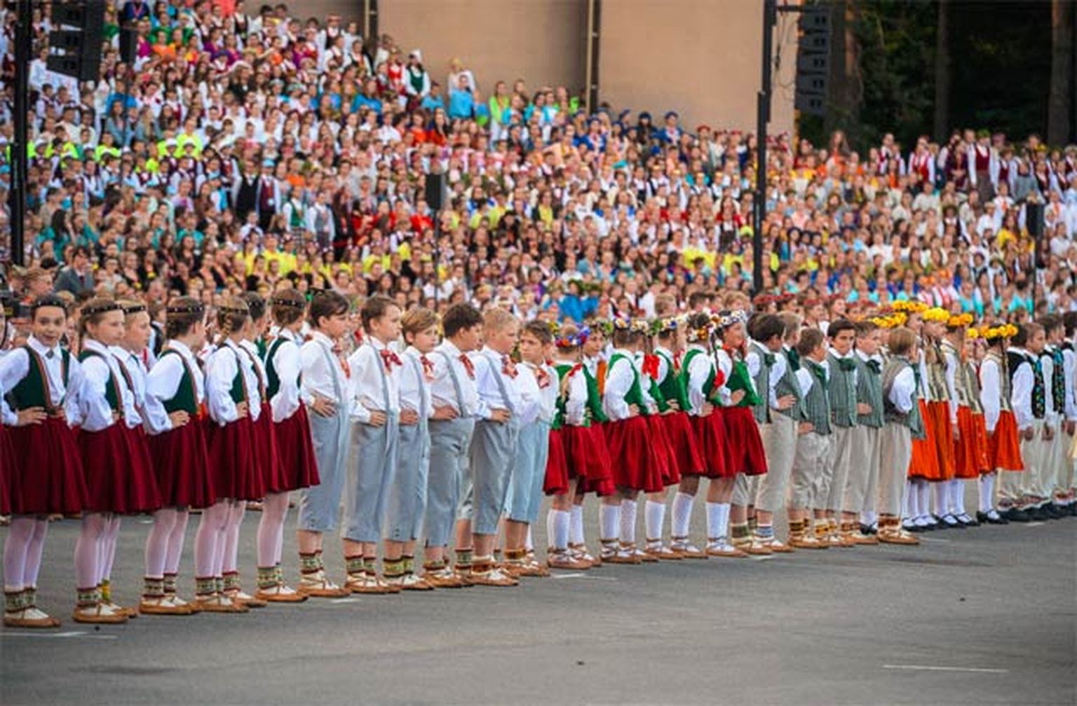 Skolēnu dziesmu un deju svētku dalībnieki un apmeklētāji dzied Latvijas himnu