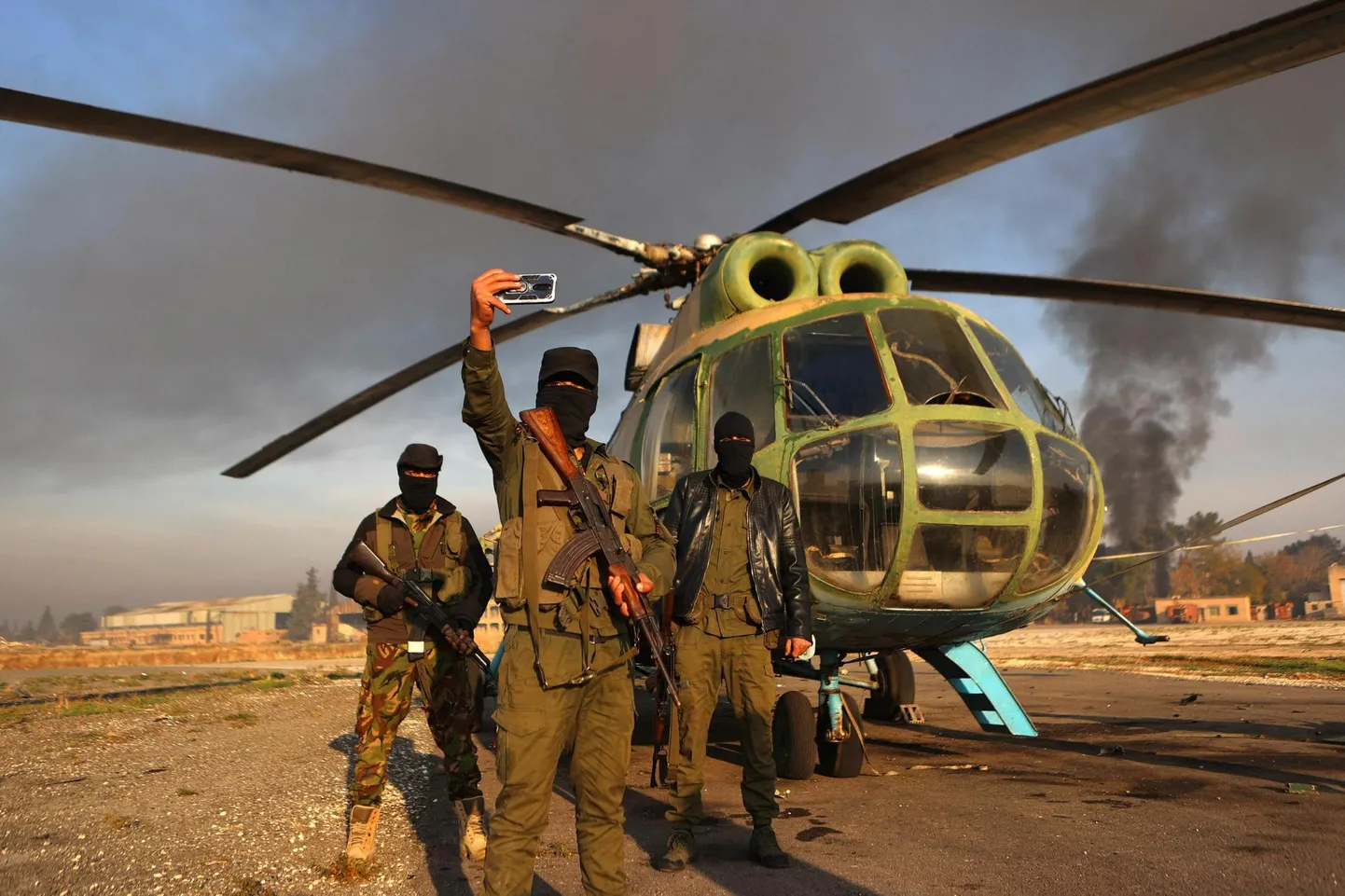 Süüria režiimivastased võitlejad poseerivad esmaspäeval Aleppos Nayrabi sõjaväebaasis helikopteri juures, mille taandunud armee maha jättis.