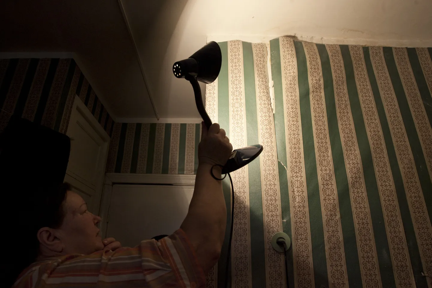 Другая жительница общежития Леонида Орлова демонстрирует протекший потолок и отошедшие от стен обои в своей комнате.