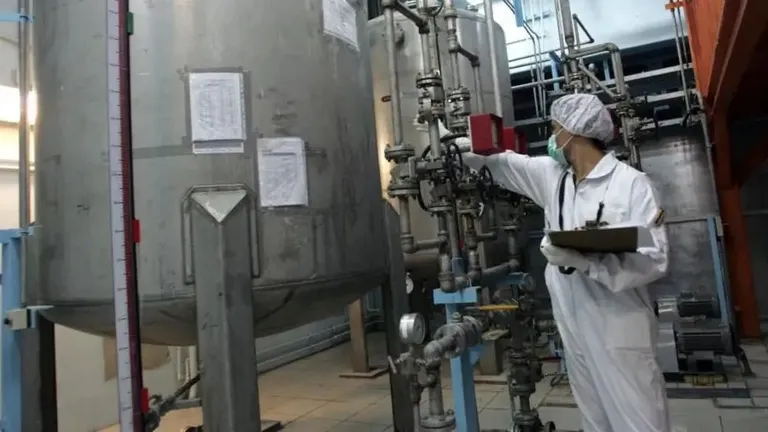 Человек в белом комбинезоне крутит вентиль на иранском ядерном объекте в Исфахане