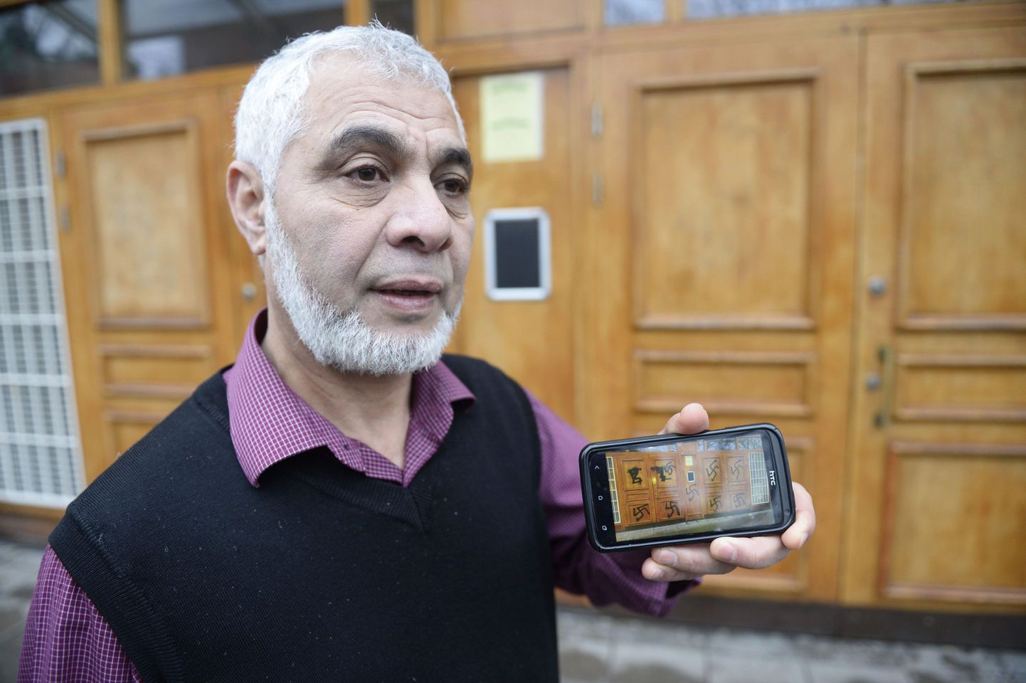 Imaam Mahmoud Khalfi näitab mošee välisuksest tehtud pilte.