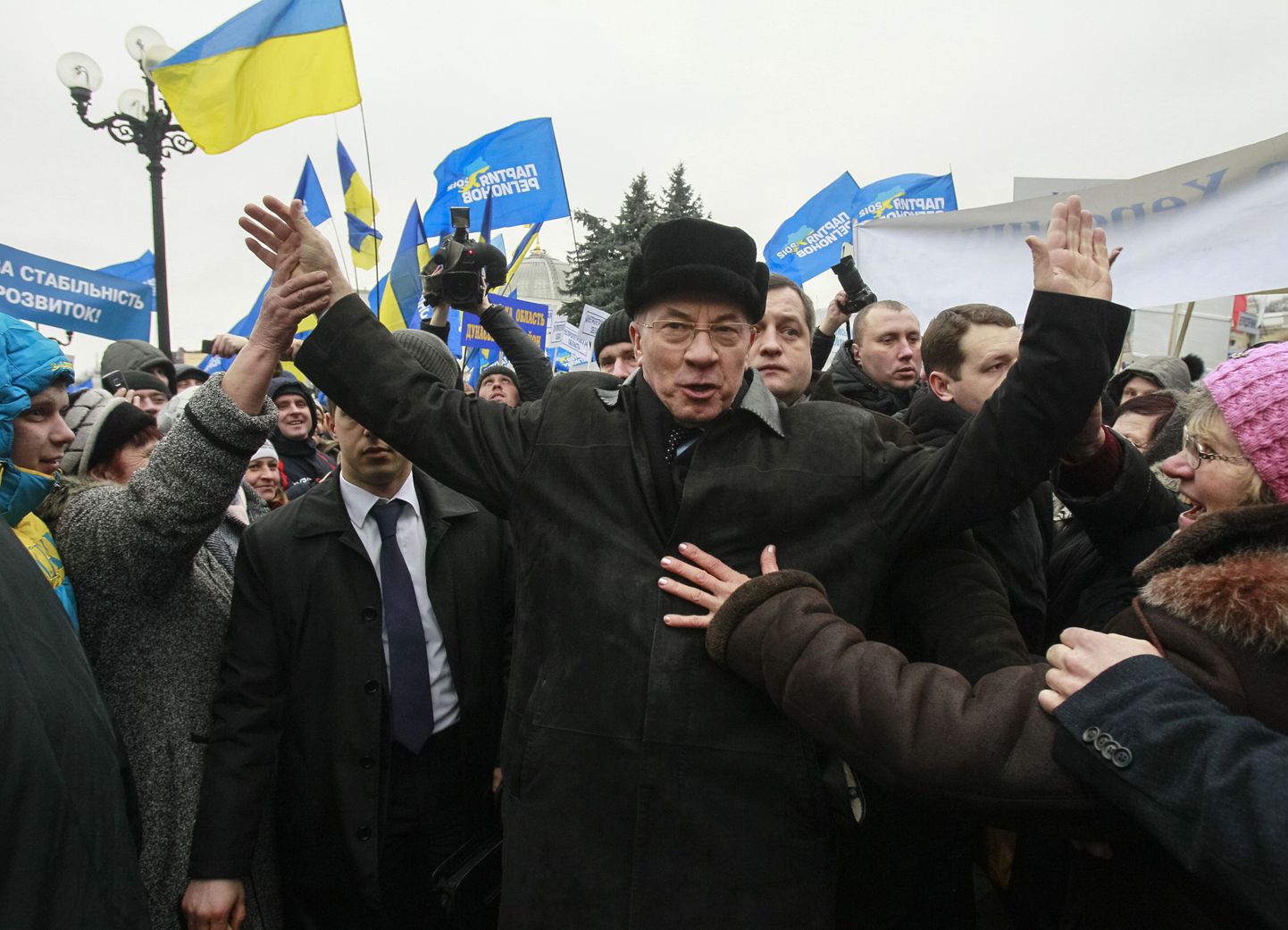 Ukraina peaminister Mõkola Azarov (keskel) koos oma poolehoidjatega. Taustal lehvivad Regioonide Partei ja Ukraina lipud.