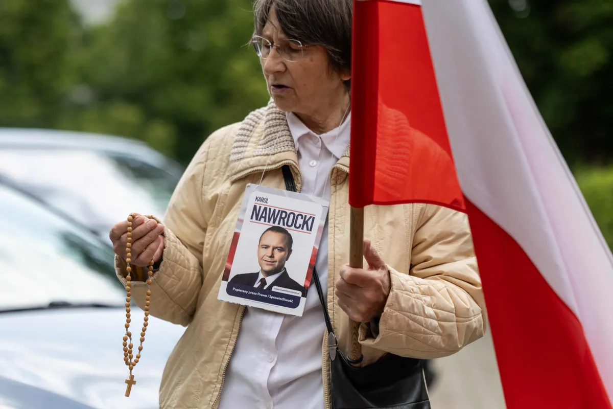 An opponent of Poland's Prime Minister Donald Tusk holds portrait of President-elect Karol Nawrocki and a rosary in front of Parliament before the vote of confidence for his cabinet in Warsaw on June 11, 2025.