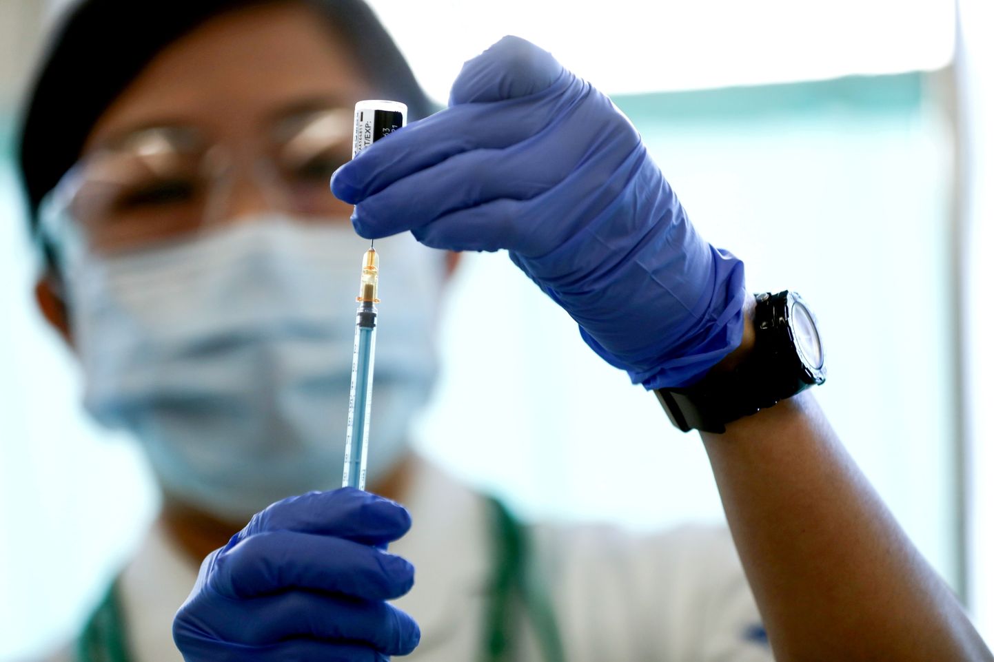 Meditsiinitöötaja täitmas süstalt Pfizer-BioNTechi vaktsiinidoosiga