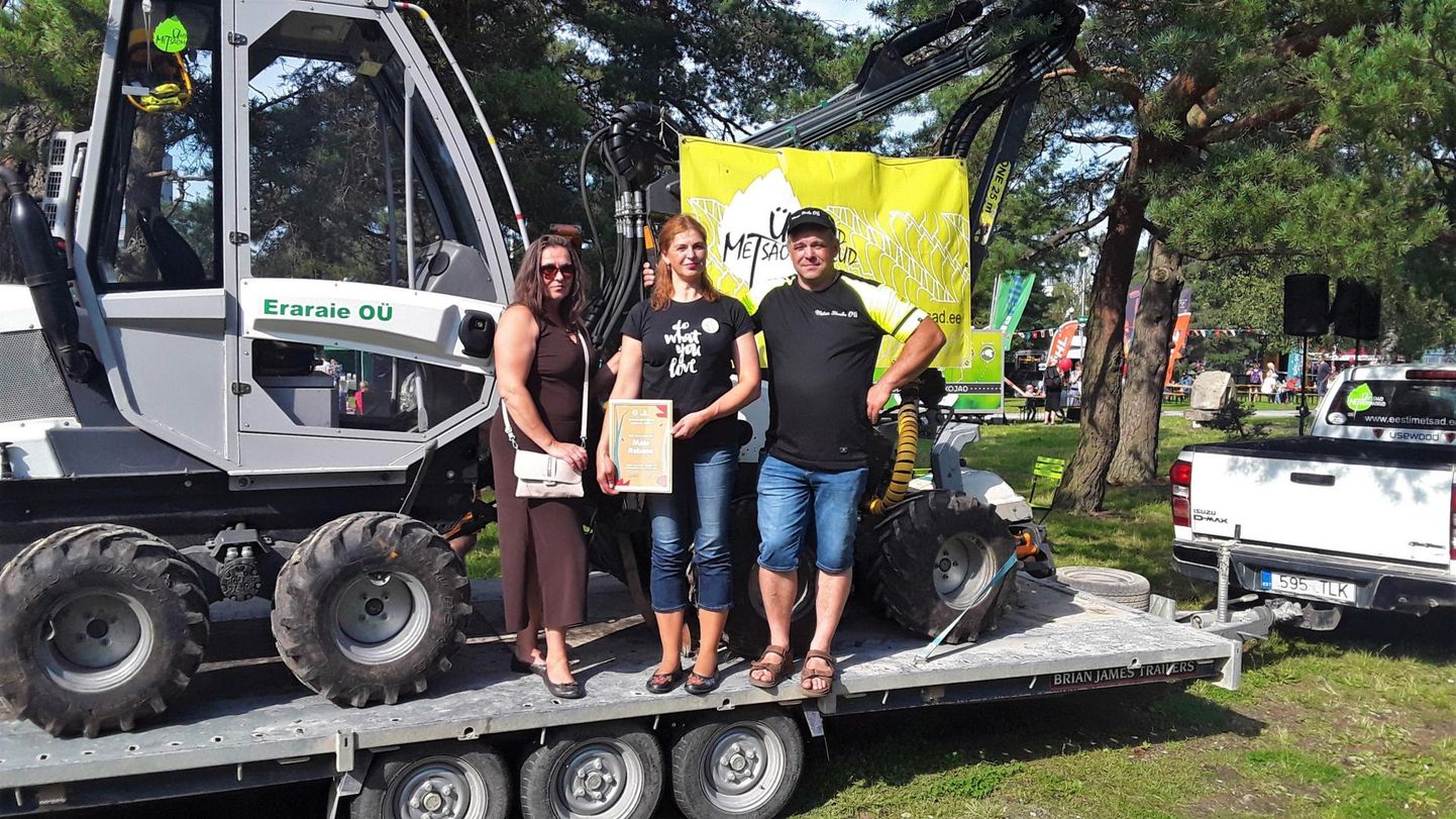 Parima metsmajandaja konkursil osalenud Maie Rebane (keskel) koos õe Kaie Tiiveli ja miniharvesteril töötava venna Tõnu Tiiveliga.
